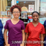 Four young women standing outside a building, wearing scrubs in various colors (blue, burgundy, red, and purple). They are part of a Summer Youth Employment Program, as indicated by the text at the bottom of the image. Each individual has a confident, professional demeanor, suggesting they are participating in a healthcare-related or community service program. The background includes signage for a business, possibly related to massage therapy or medical services.