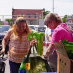 A client receiving fresh produce at a Feeding Our Neighbor food distribution.