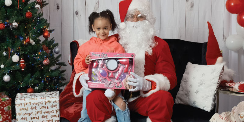 FY26-Christmas-Year-End-Popup-1 A child with Santa at Betances Houses.